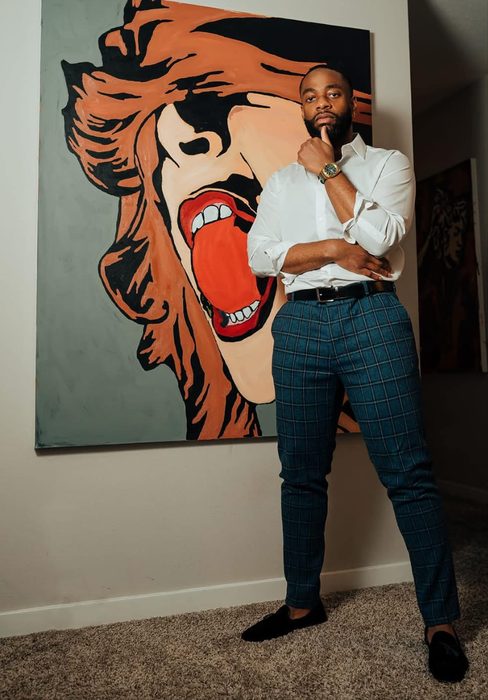 Willie Austin leaning against his pop art painting of a woman's face with an open red mouth