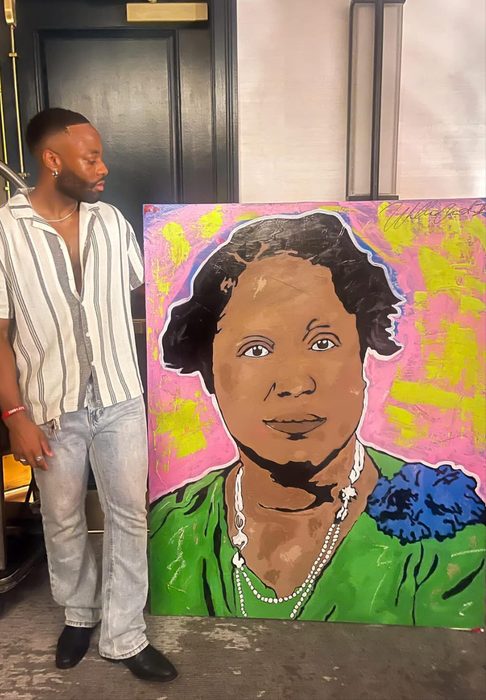 Willie Austin standing beside his pink, green and yellow portrait of a woman wearing pearls